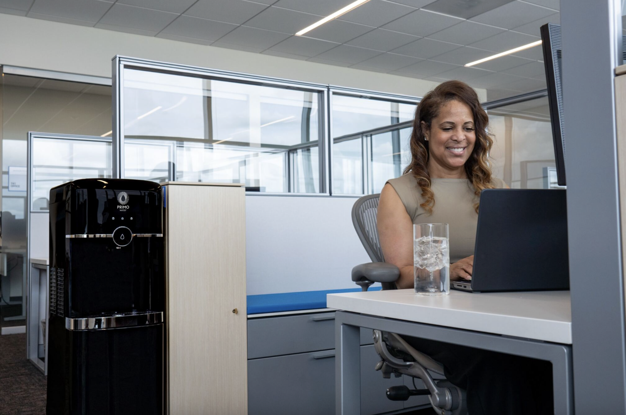 woman working at desk with water how to stay hydrated at work